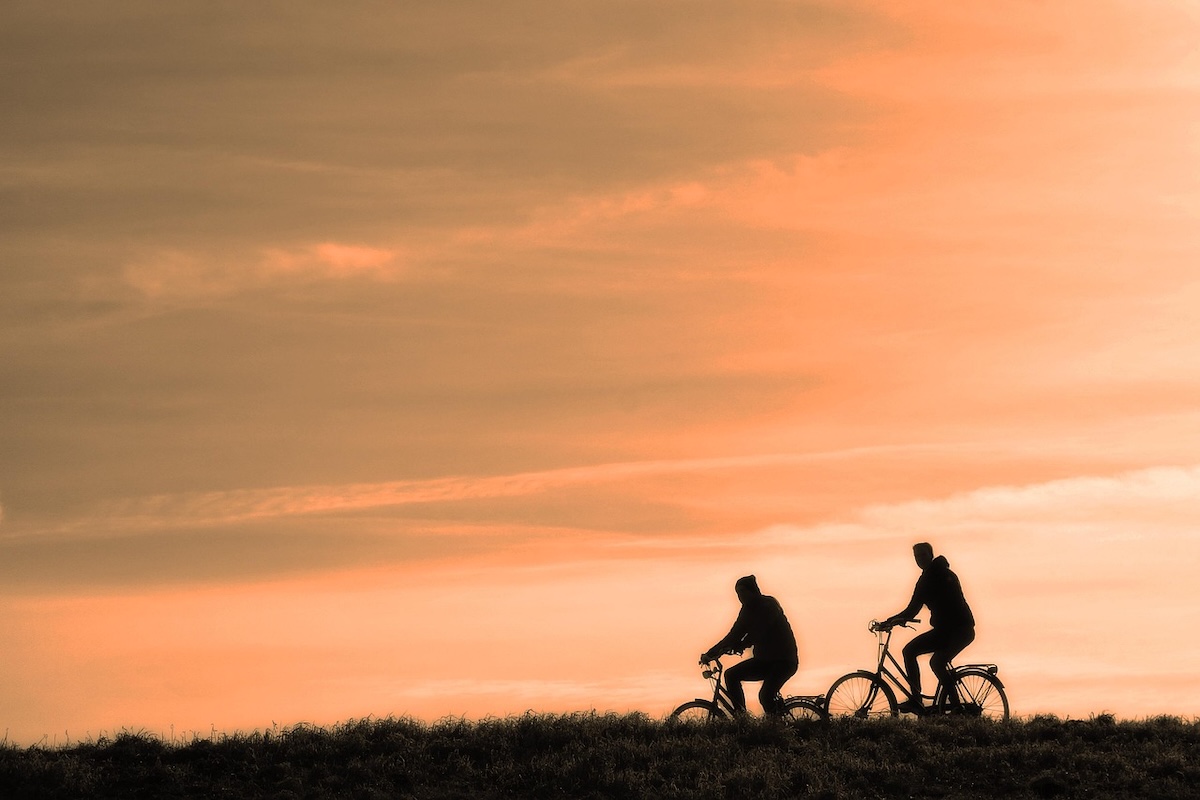 Deux personnes circulant à vélo sur une voie au levé du soleil